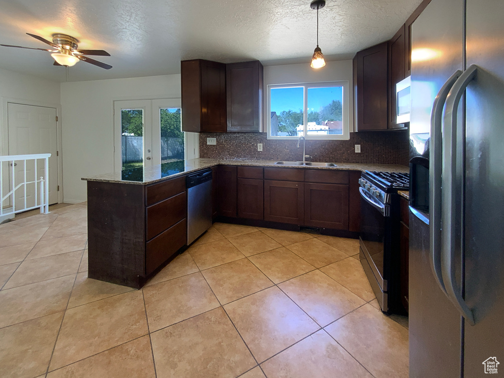 Kitchen with stainless steel appliances, a sink, decorative backsplash, light stone countertops, and a textured ceiling