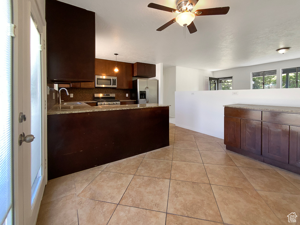 Kitchen featuring stainless steel appliances, a sink, a peninsula, decorative backsplash, and ceiling fan
