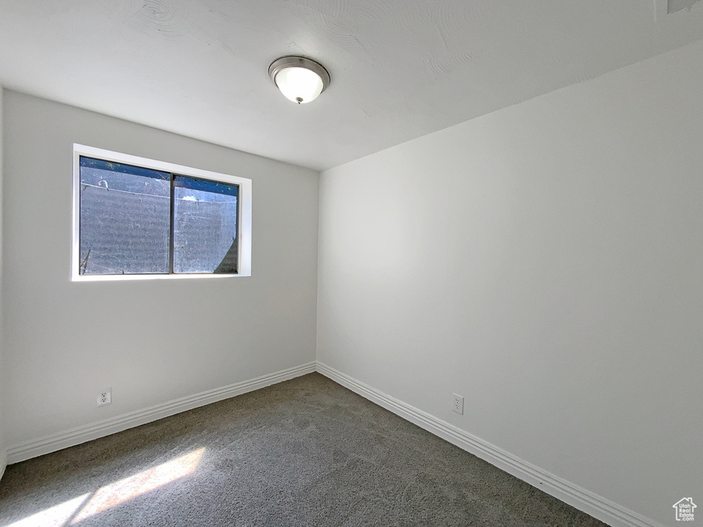 Empty room with dark carpet and baseboards