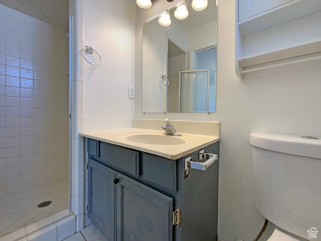 Bathroom featuring toilet, vanity, and tiled shower