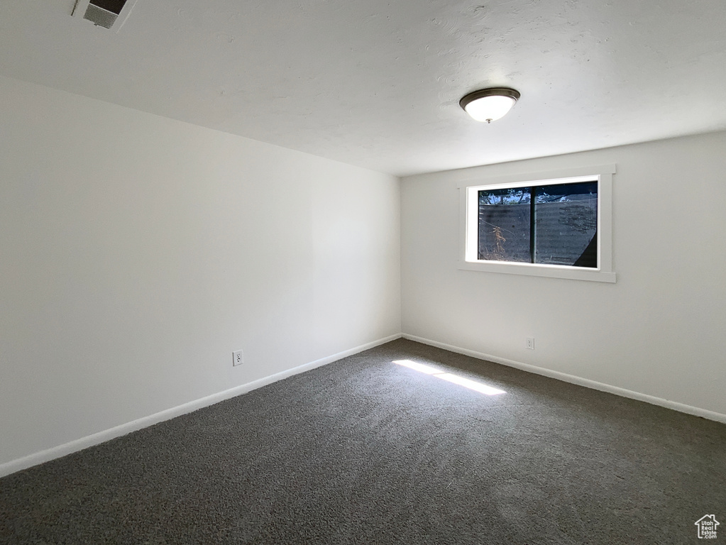 Empty room with dark colored carpet and baseboards