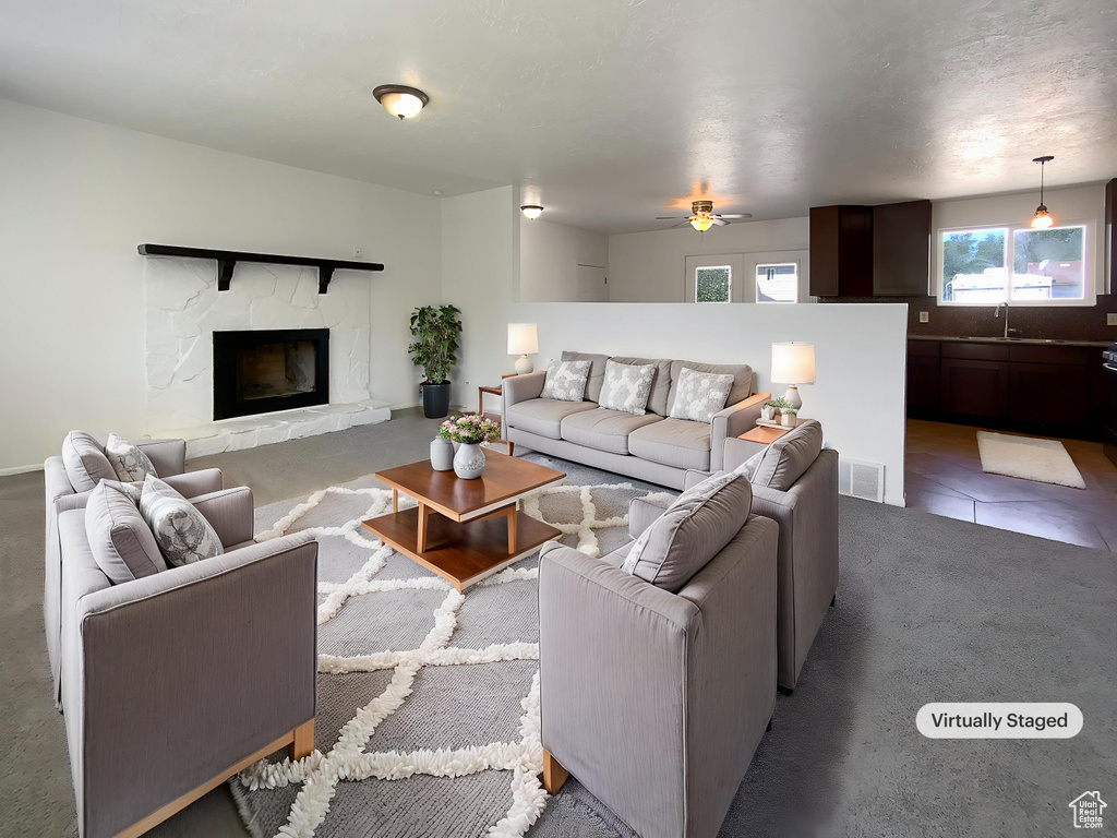 Carpeted living room featuring a sink, ceiling fan, and a fireplace
