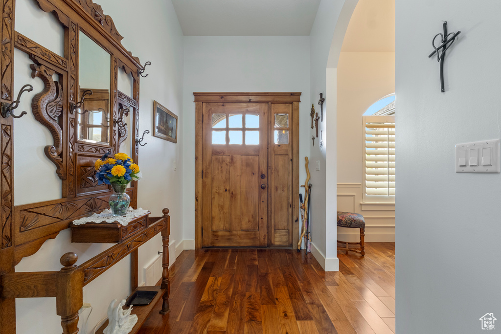 Foyer featuring arched walkways and dark wood finished floors