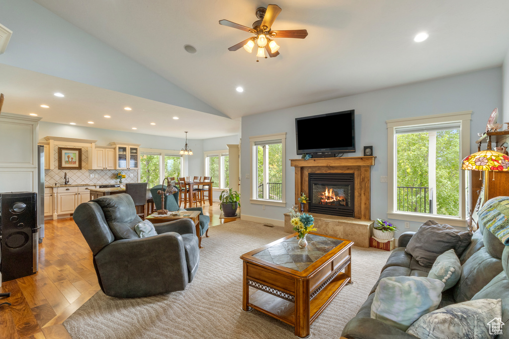 Living area with recessed lighting, healthy amount of natural light, vaulted ceiling, a glass covered fireplace, and a ceiling fan