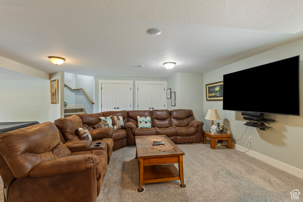 Living room featuring baseboards, stairway, and light carpet