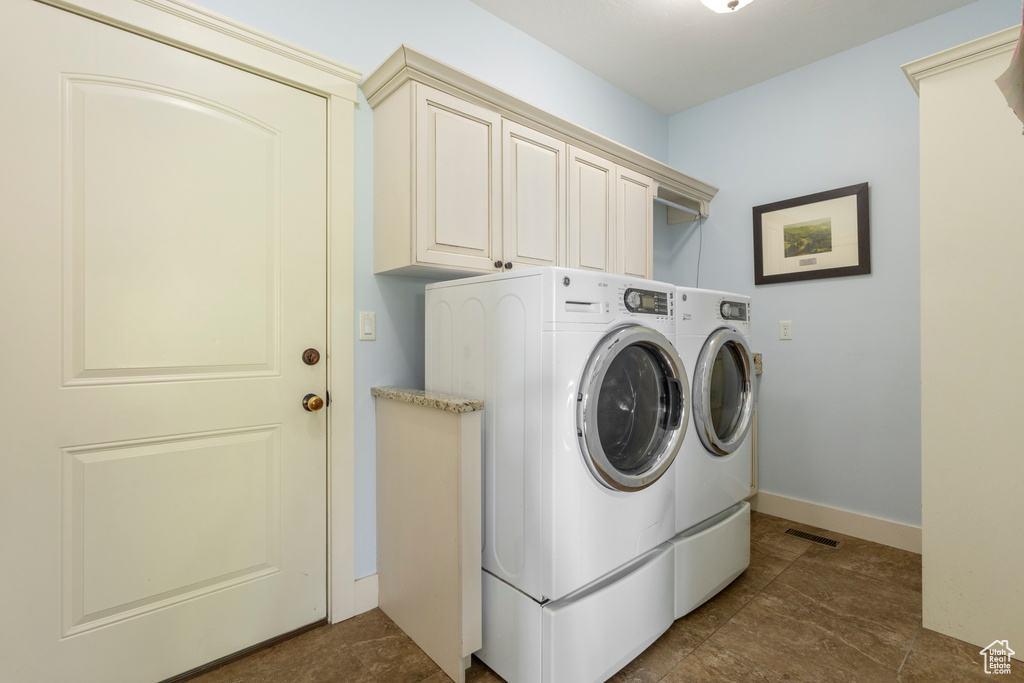 Washroom with washer and clothes dryer, cabinet space, and baseboards