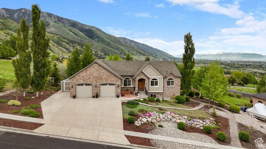 View of front facade with a garage, a mountain view, stone siding, and concrete driveway