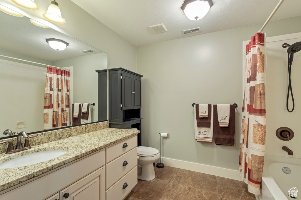 Bathroom with toilet, baseboards, vanity, and shower / bath combination with curtain
