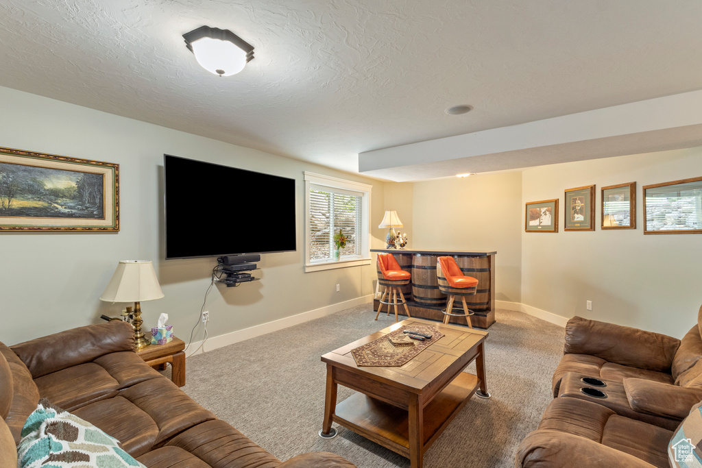 Carpeted living room with a dry bar, baseboards, and a textured ceiling