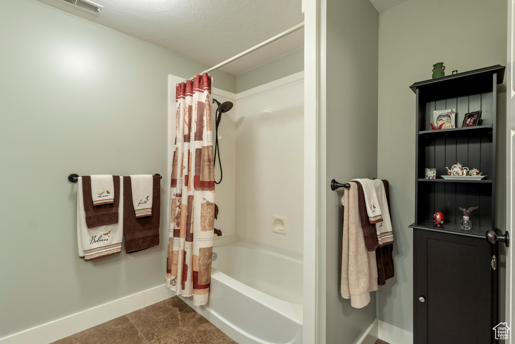 Bathroom with baseboards and shower / bathtub combination with curtain
