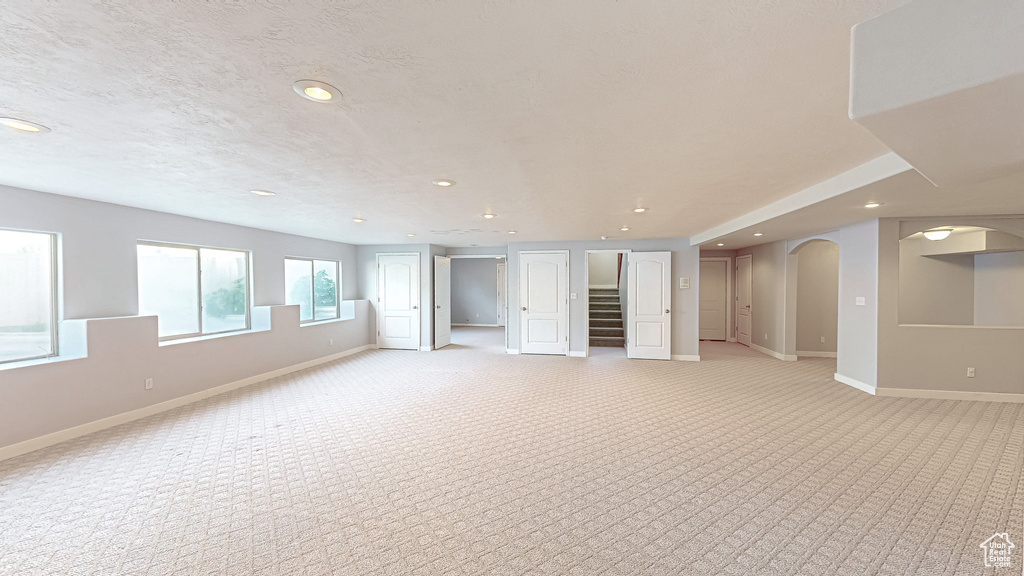 Below grade area with baseboards, light colored carpet, recessed lighting, and stairway