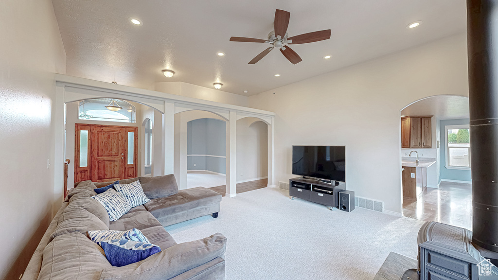 Living area with a ceiling fan, light colored carpet, recessed lighting, and arched walkways