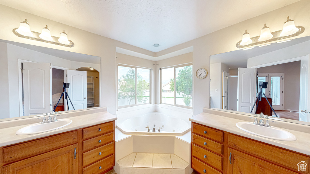 Full bath featuring two vanities, a tub with jets, and a shower