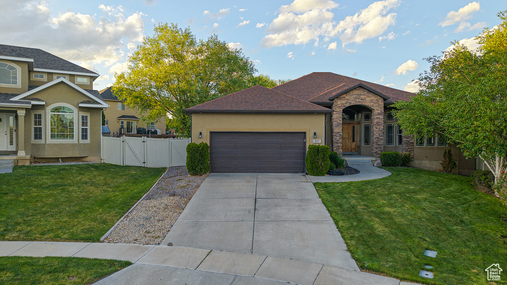 View of front of home with a gate, an attached garage, driveway, and stucco siding