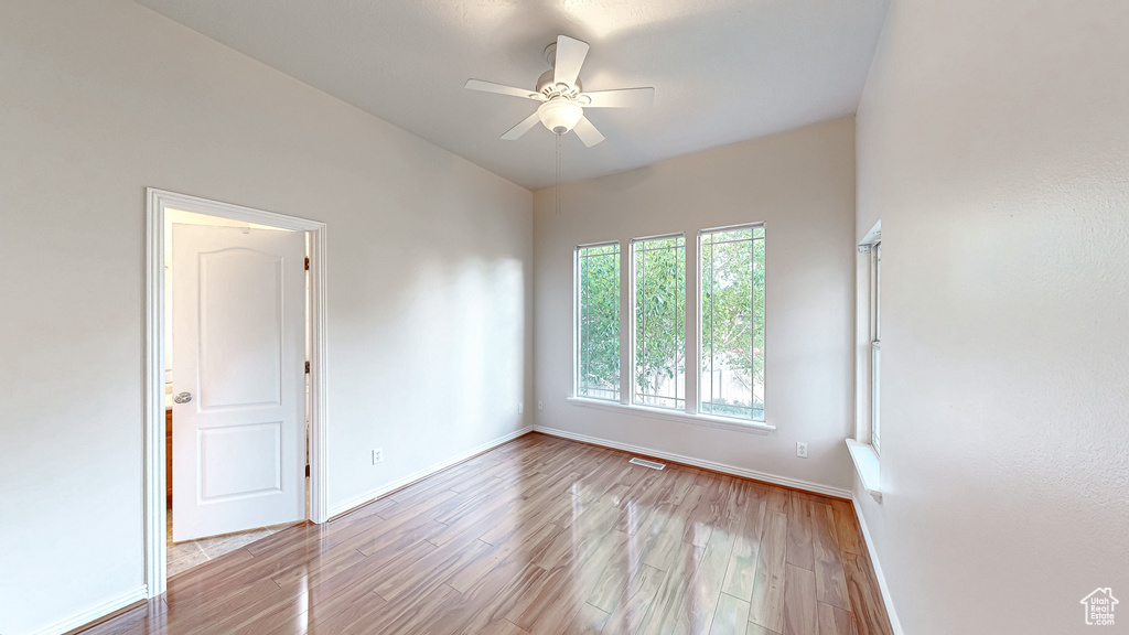 Empty room with a ceiling fan, wood finished floors, and baseboards