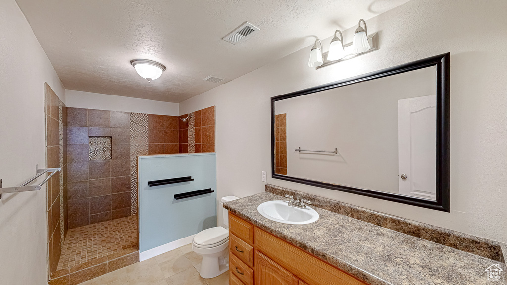 Bathroom featuring walk in shower, vanity, toilet, and tile patterned floors