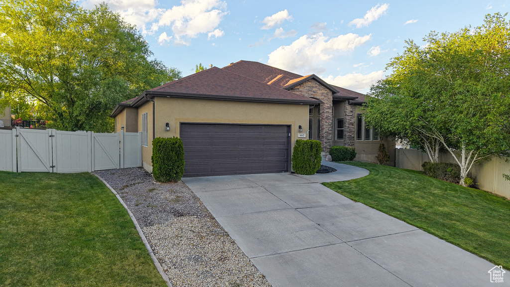 Single story home with a gate, stucco siding, an attached garage, driveway, and stone siding