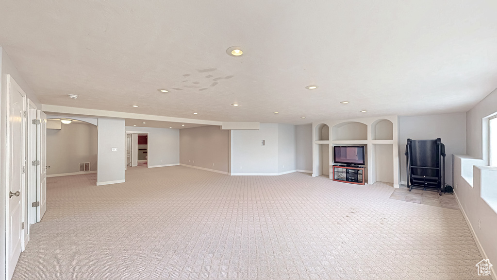 Unfurnished living room with recessed lighting, light colored carpet, and baseboards