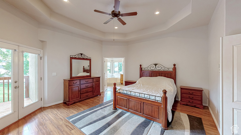 Bedroom featuring access to outside, multiple windows, light wood-style floors, a tray ceiling, and recessed lighting