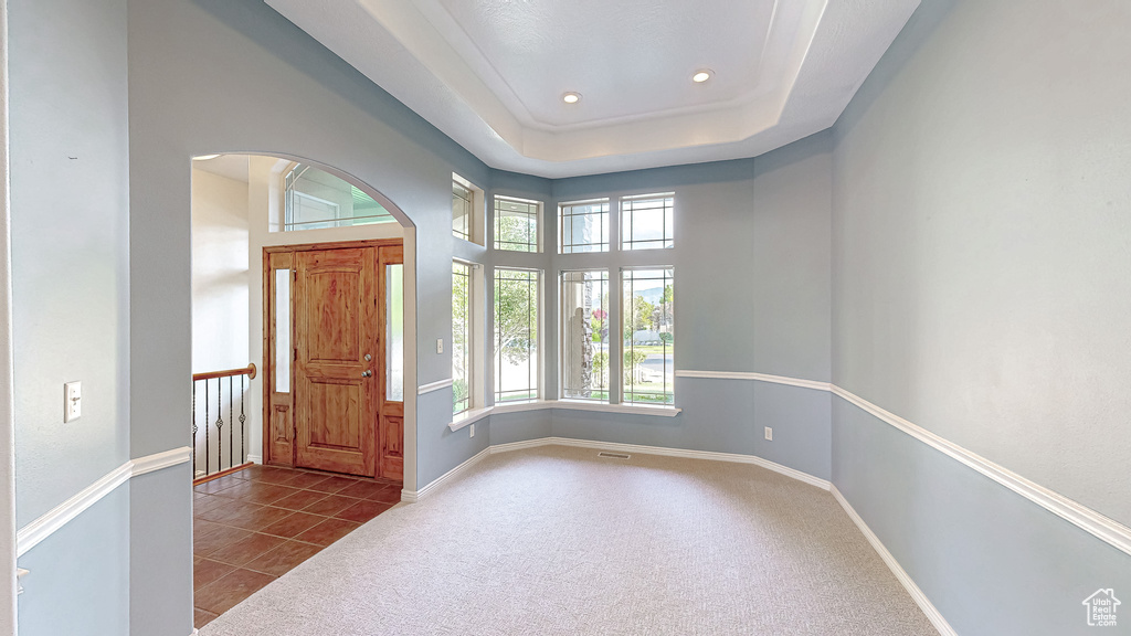 Entrance foyer featuring arched walkways, tile patterned flooring, baseboards, recessed lighting, and carpet floors
