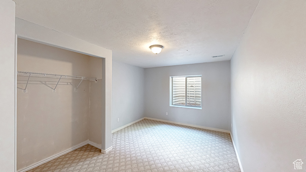 Unfurnished bedroom featuring carpet, a closet, baseboards, and a textured ceiling