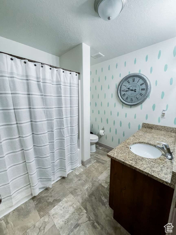 Full bath featuring wallpapered walls, vanity, toilet, a textured ceiling, and a shower with curtain