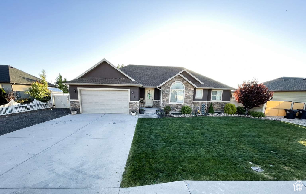 Ranch-style house with an attached garage, stone siding, driveway, a gate, and stucco siding