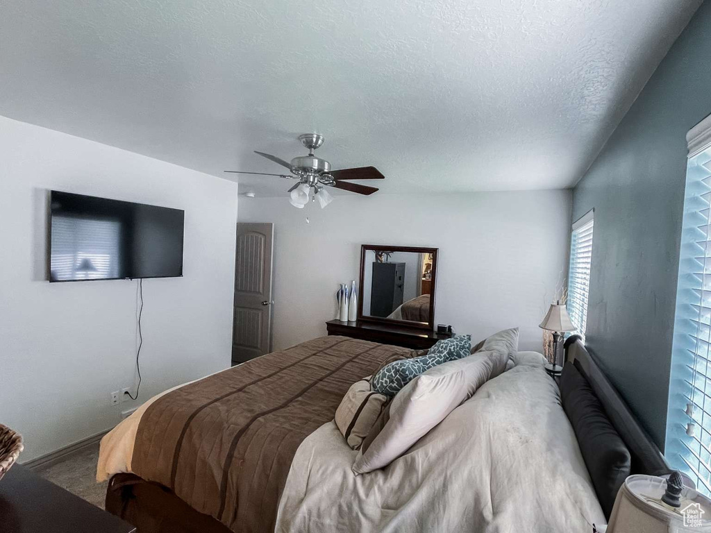 Bedroom featuring ceiling fan, carpet floors, and a textured ceiling