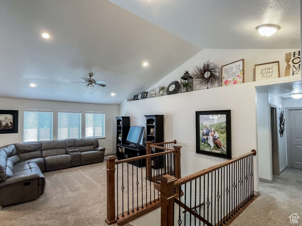 Carpeted living area featuring lofted ceiling, a ceiling fan, and recessed lighting