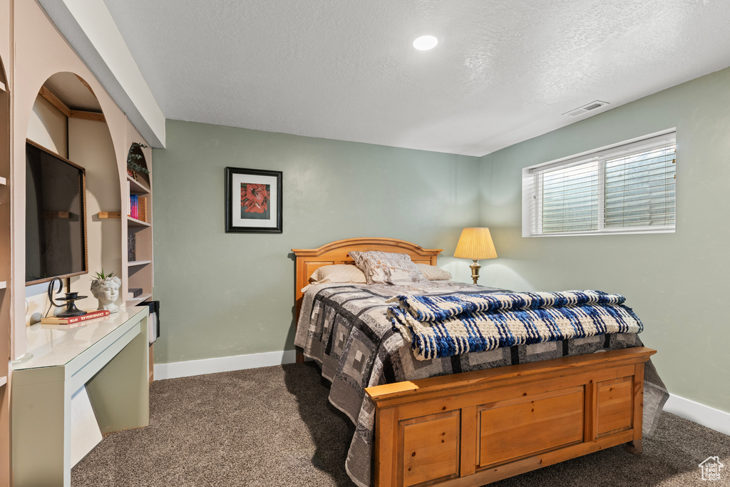 Bedroom featuring carpet, baseboards, and a textured ceiling