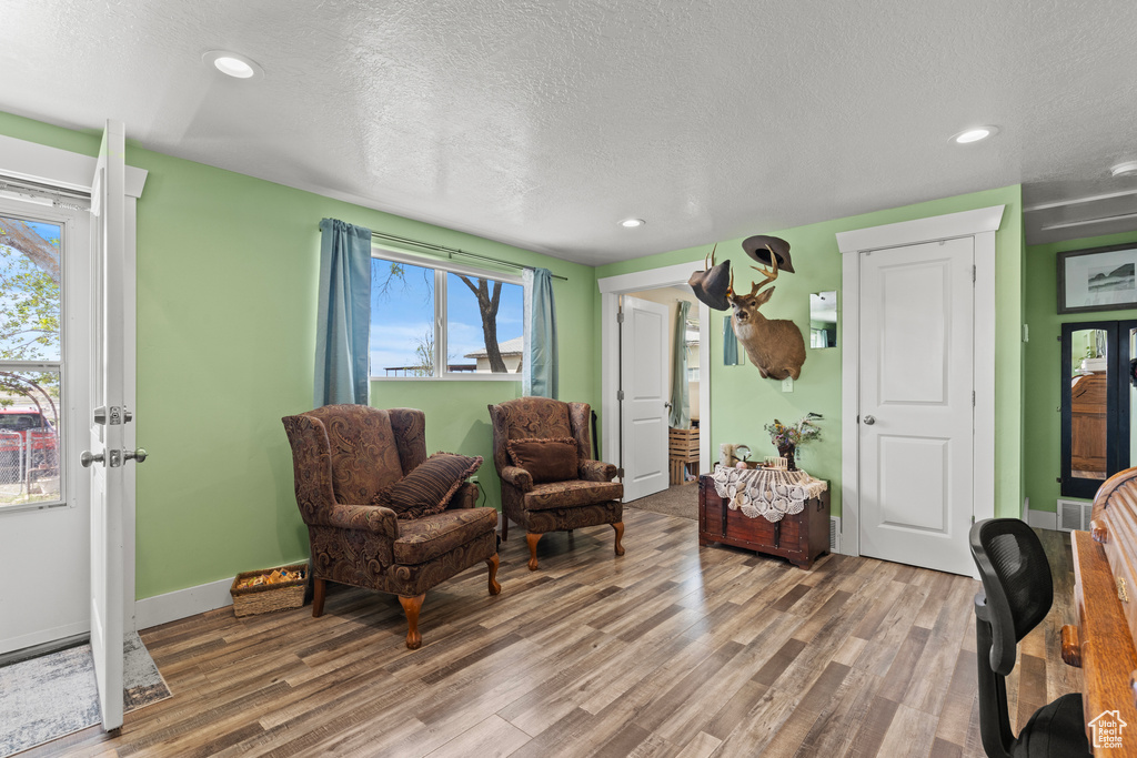 Sitting room with wood finished floors, a textured ceiling, plenty of natural light, baseboards, and recessed lighting
