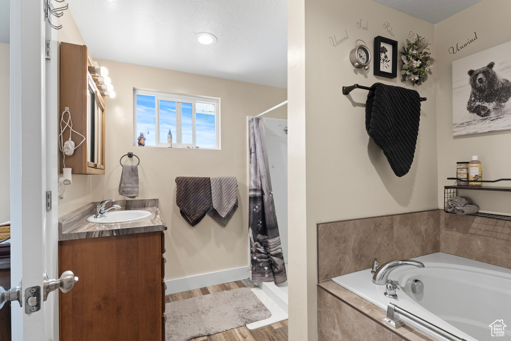 Bathroom featuring vanity, a garden tub, wood finished floors, baseboards, and a shower with shower curtain
