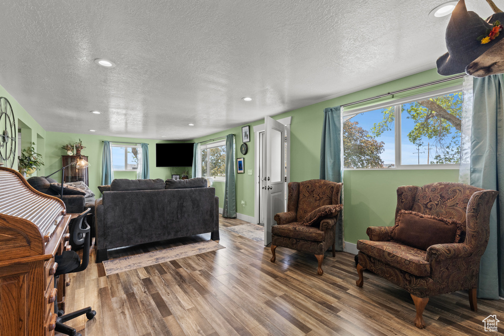 Living area featuring a textured ceiling, wood finished floors, recessed lighting, and baseboards