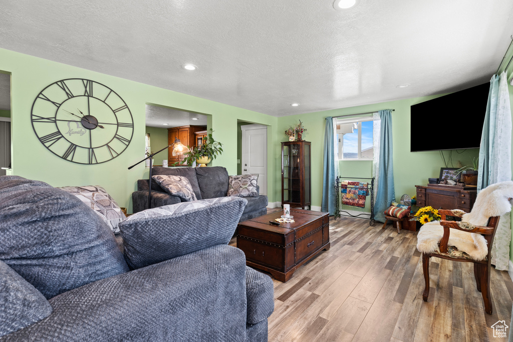 Living room featuring light wood-type flooring, recessed lighting, and a textured ceiling