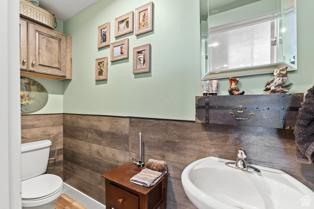 Half bath featuring toilet, a sink, and wainscoting