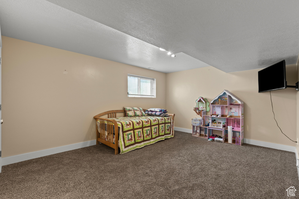 Carpeted bedroom featuring a textured ceiling and baseboards