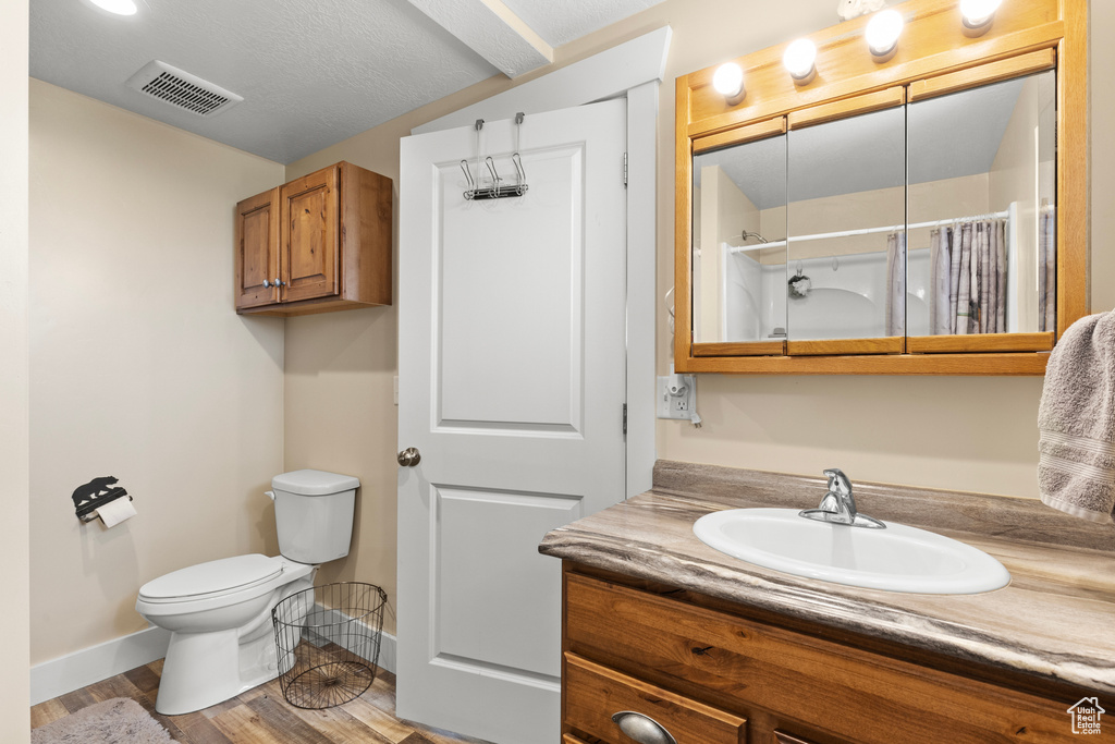 Full bathroom with toilet, vanity, a shower with curtain, baseboards, and wood finished floors