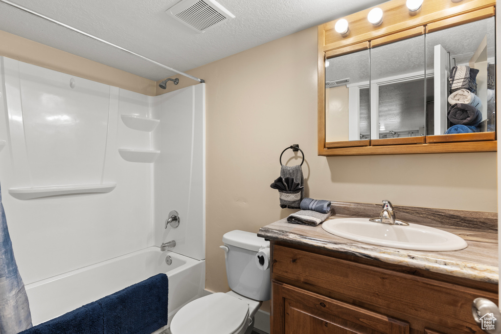 Bathroom featuring vanity, bathing tub / shower combination, toilet, and a textured ceiling