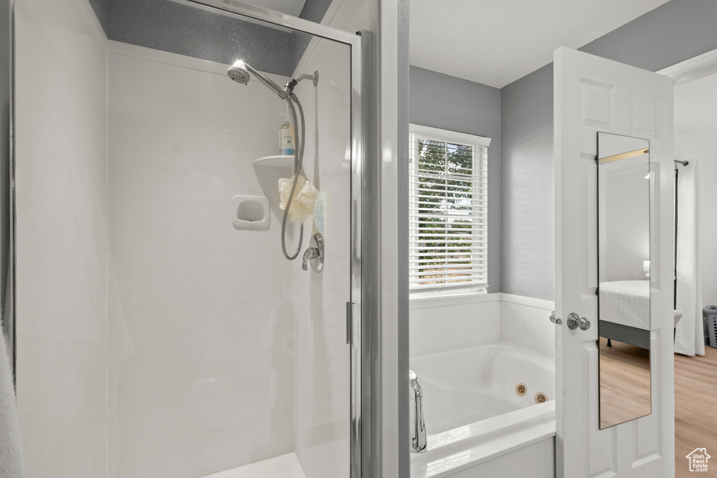 Full bathroom featuring a shower stall, a whirlpool tub, wood finished floors, and ensuite bathroom