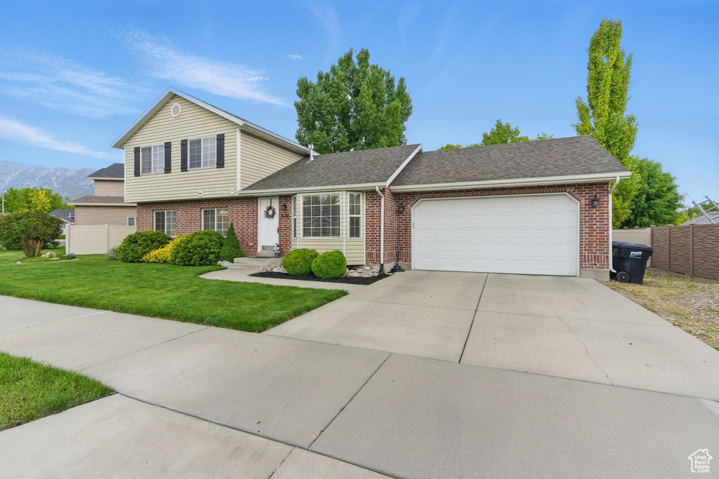View of front of home with an attached garage, brick siding, a shingled roof, and concrete driveway