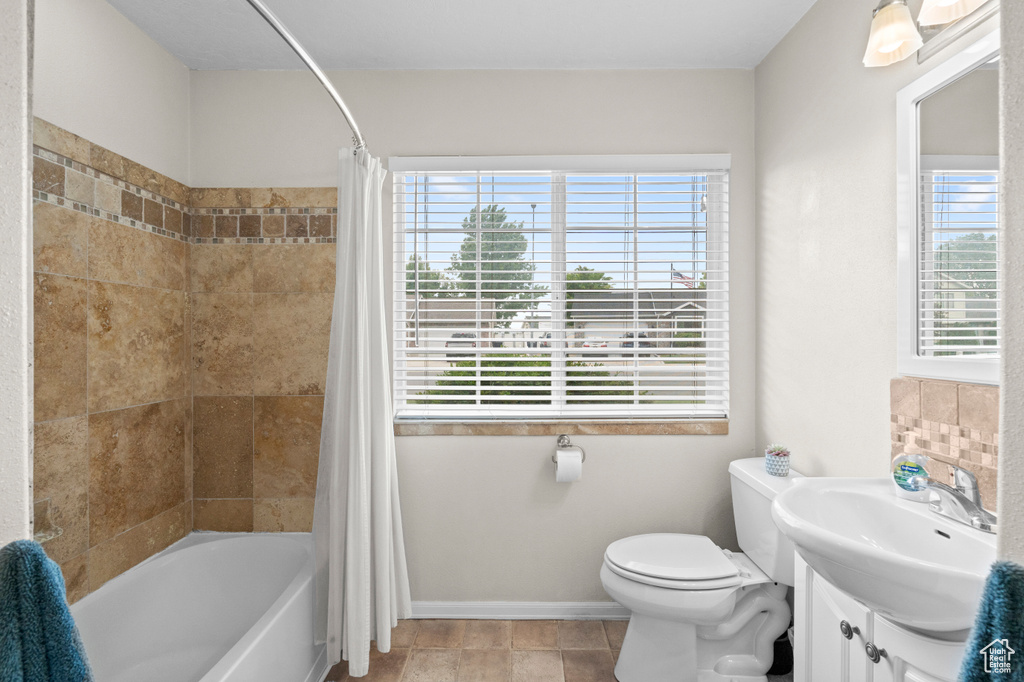 Bathroom with toilet, shower / tub combo, vanity, and baseboards