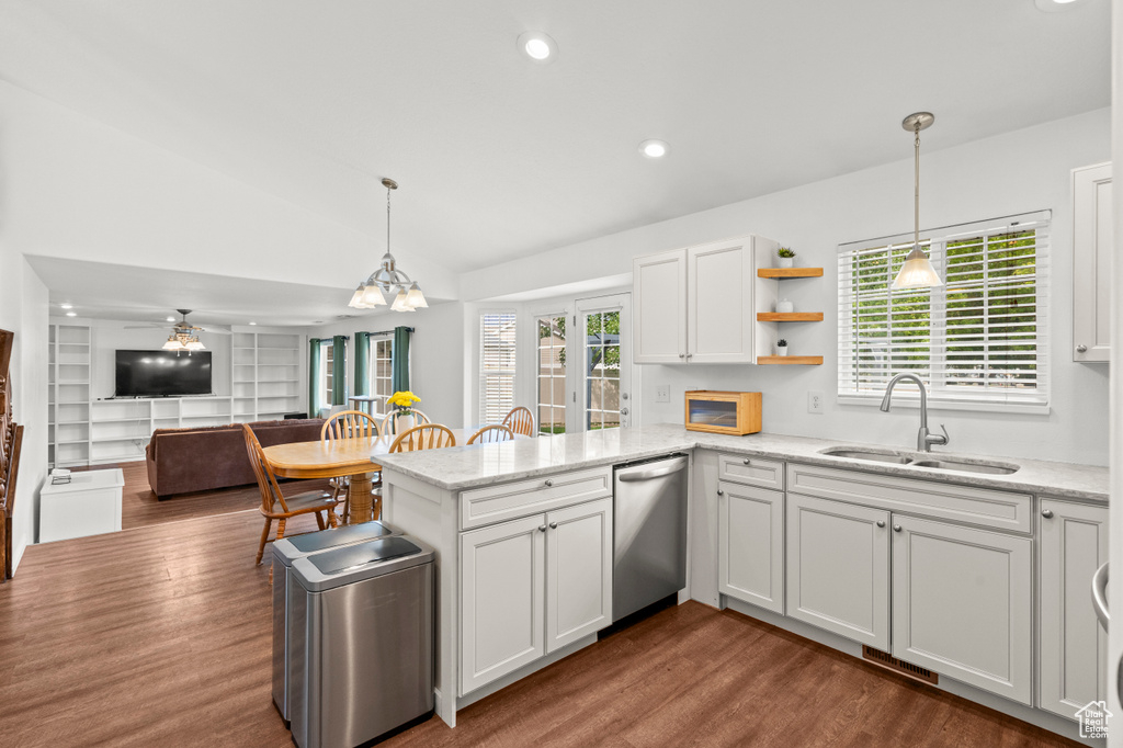 Kitchen featuring a sink, stainless steel dishwasher, dark wood-type flooring, a peninsula, and lofted ceiling