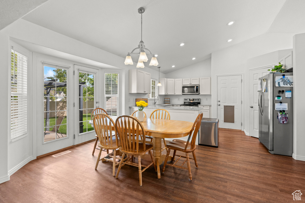 Dining room featuring lofted ceiling, dark wood-style flooring, recessed lighting, a chandelier, and baseboards