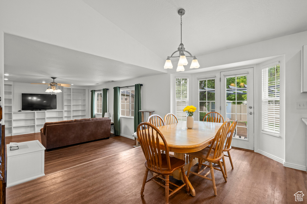 Dining space with wood finished floors, a chandelier, a ceiling fan, lofted ceiling, and baseboards