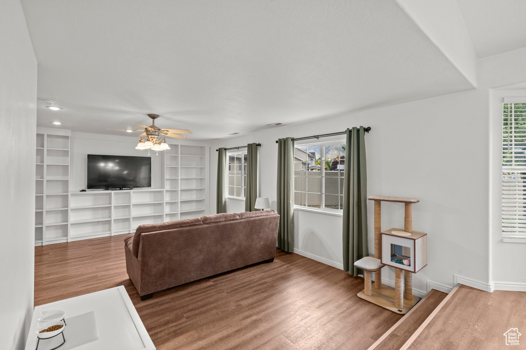 Living area with wood finished floors, ceiling fan, baseboards, recessed lighting, and built in features
