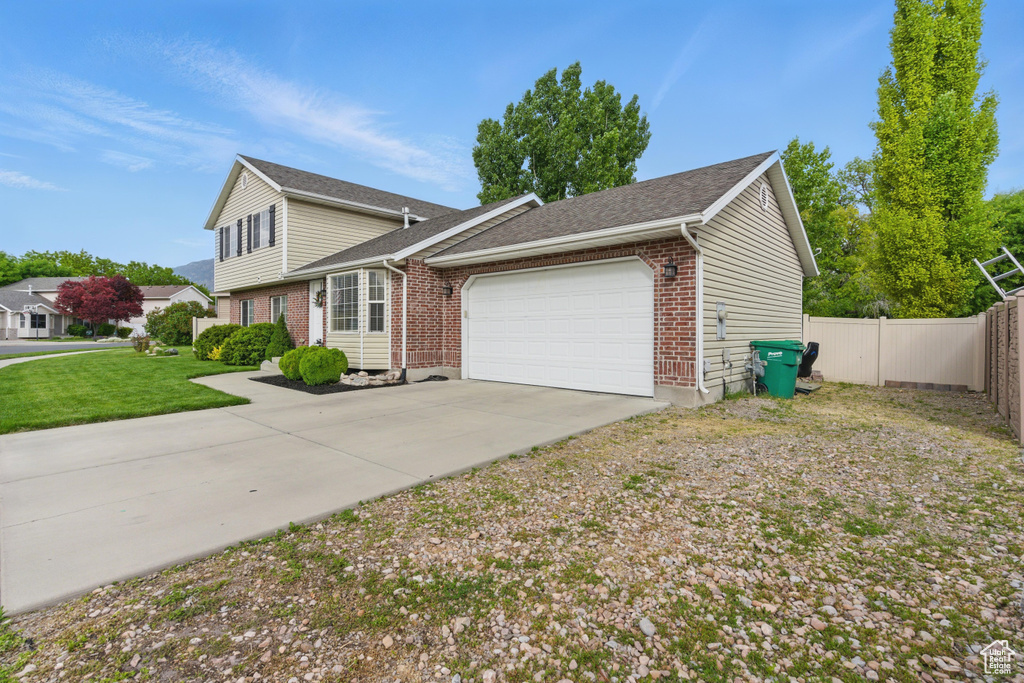 View of front of property featuring brick siding, an attached garage, driveway, and a shingled roof