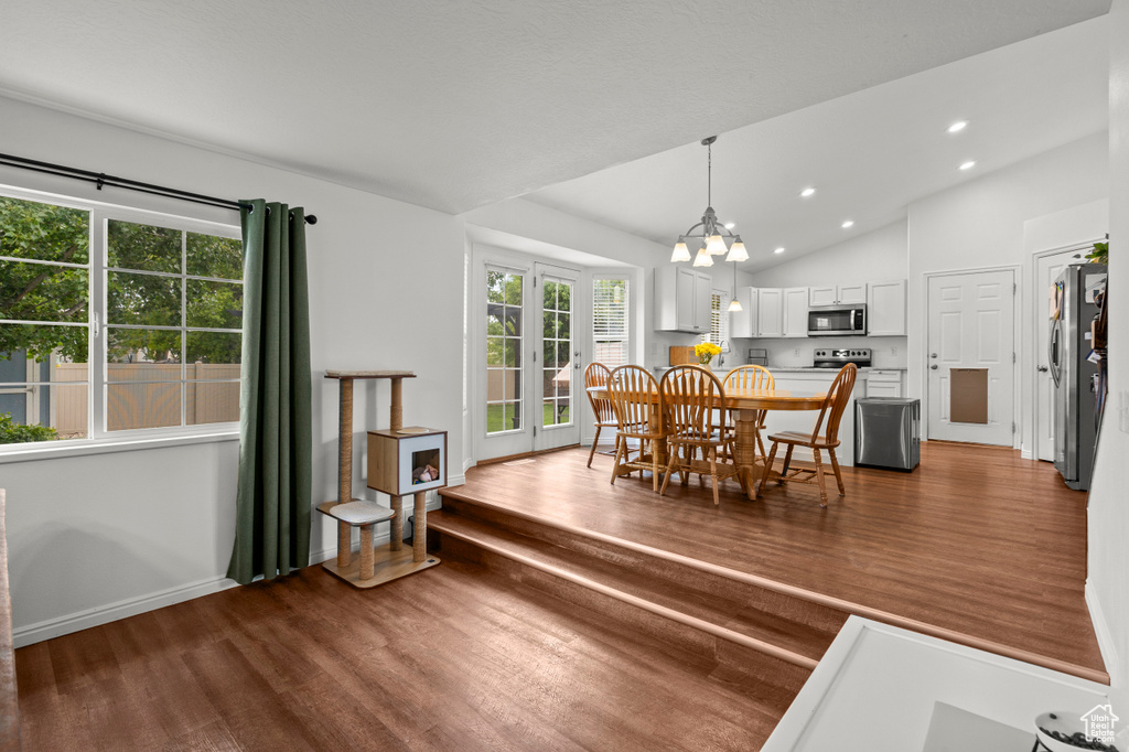 Dining room with wood finished floors, a chandelier, recessed lighting, vaulted ceiling, and baseboards