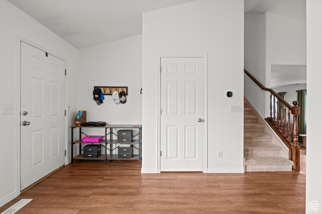 Foyer with wood finished floors, stairway, and baseboards