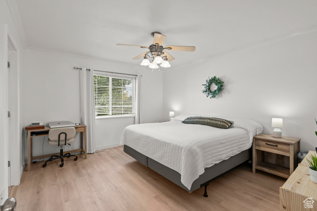 Bedroom featuring light wood-type flooring, a desk, ceiling fan, and crown molding