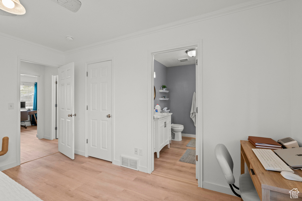 Office space featuring light wood-type flooring, crown molding, and baseboards